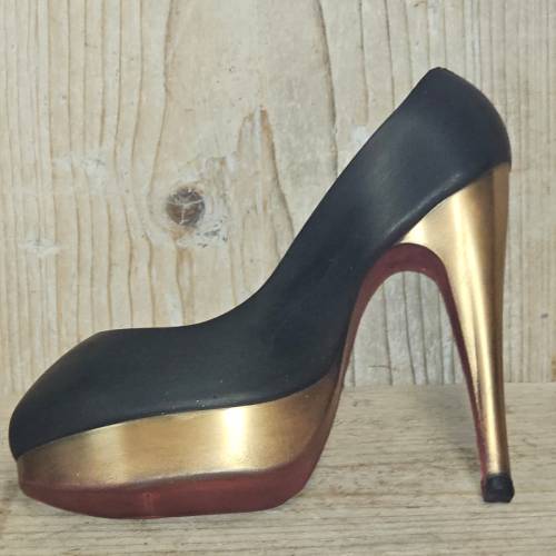 Zwart, goudkleurig en donkerrood hooggehakt schoen op een houten achtergrond.